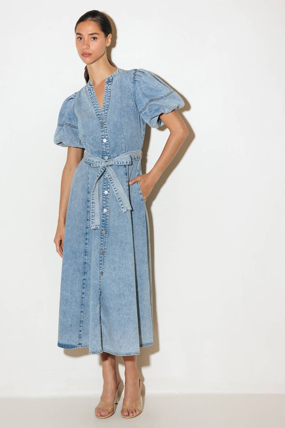 Woman wearing a denim dress with puff sleeves on a white background