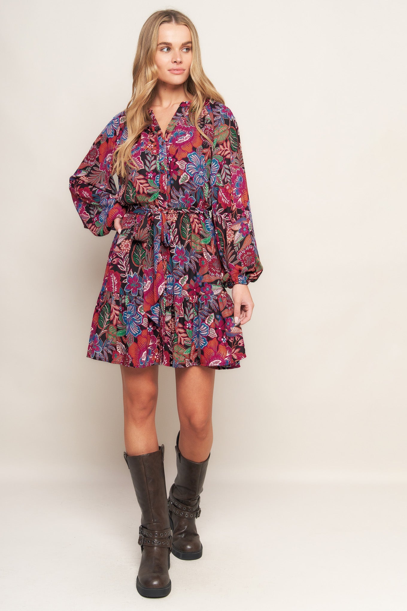 Woman wearing a colorful floral dress with long sleeves on a white background