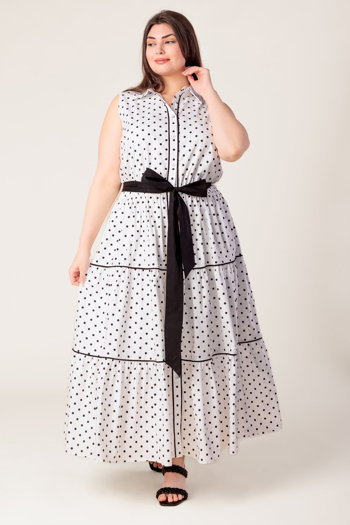 Woman wearing a polka dot dress with a black belt on a white background