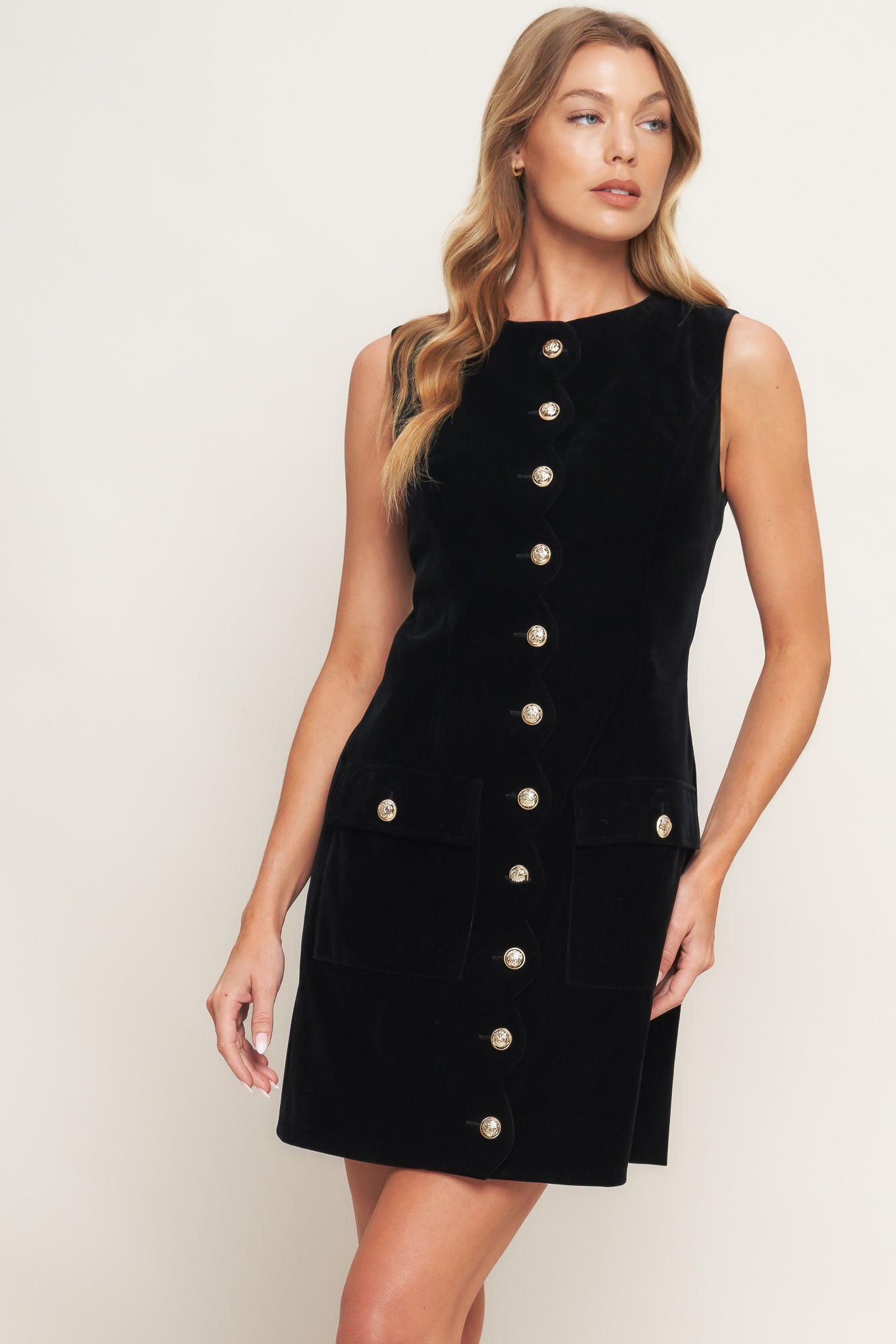 Woman wearing a black dress with button details on a white background