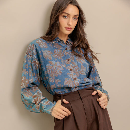 Woman wearing a blue floral blouse and brown pants against a beige background