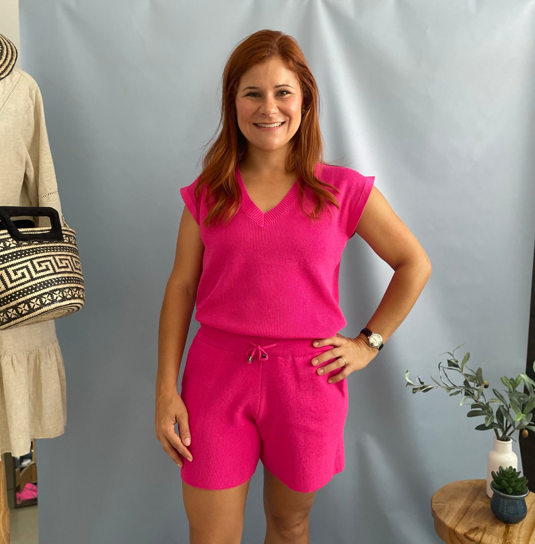 A women wearing a knitted fuchsia top and short set