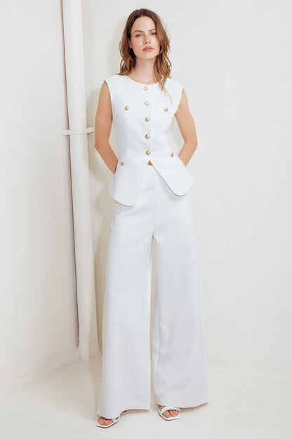 Woman wearing a white outfit with gold buttons against a white background