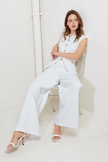 Woman in a white outfit sitting on a chair against a white background