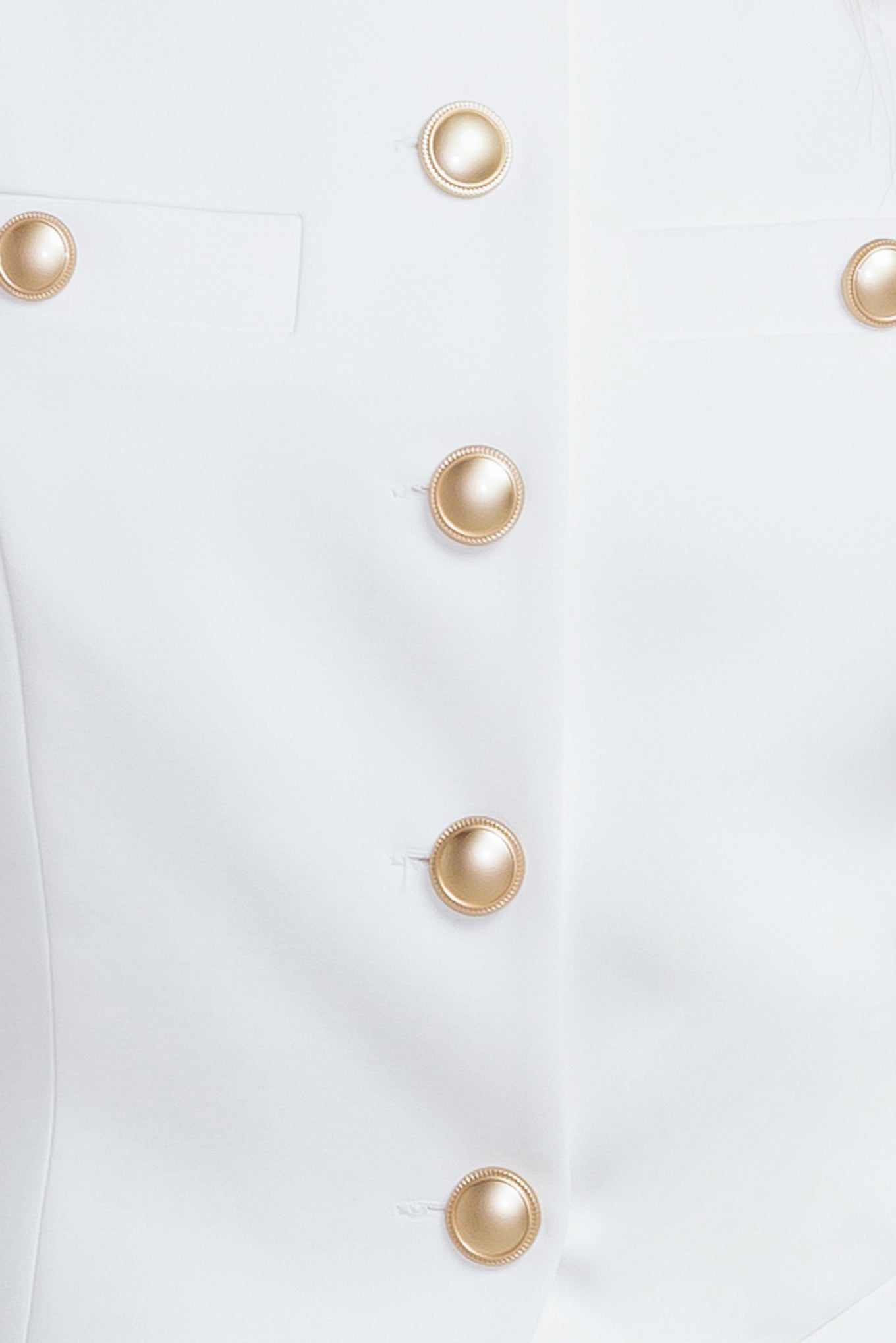 Close-up of a white garment with gold buttons on a white background