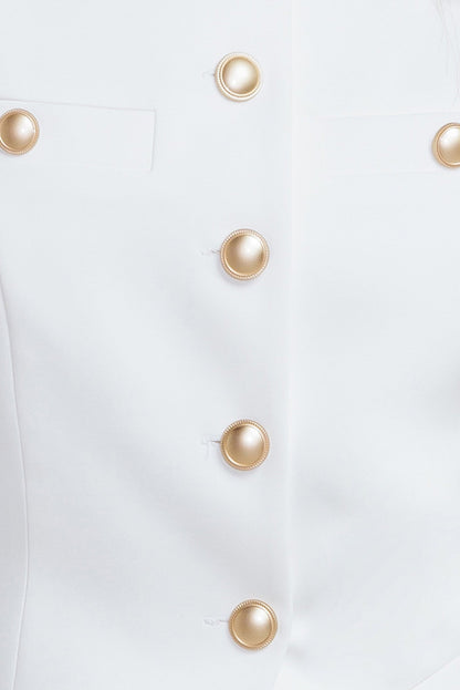 Close-up of a white garment with gold buttons on a white background