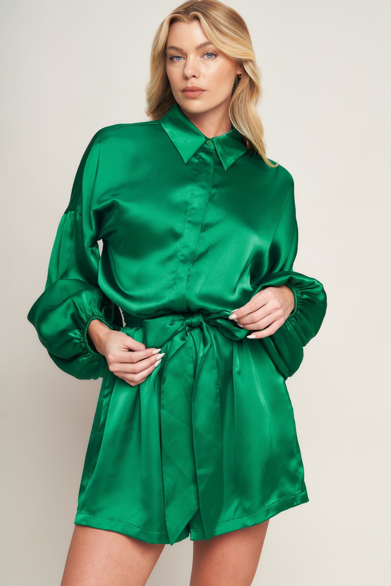 Emerald green satin romper with bishop sleeves, shirt collar, and tie waist for holiday celebrations and special events