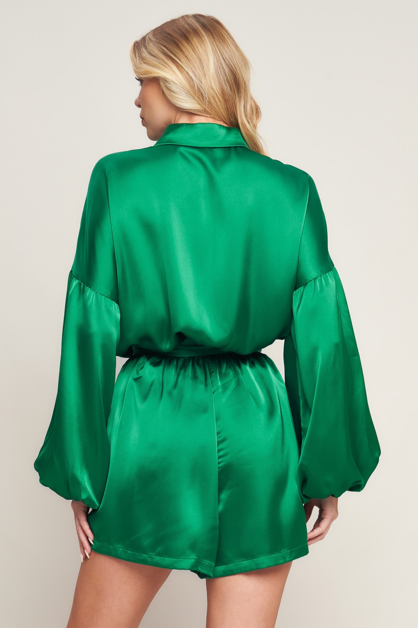 Emerald green satin romper with bishop sleeves, shirt collar, and tie waist for holiday celebrations and special events