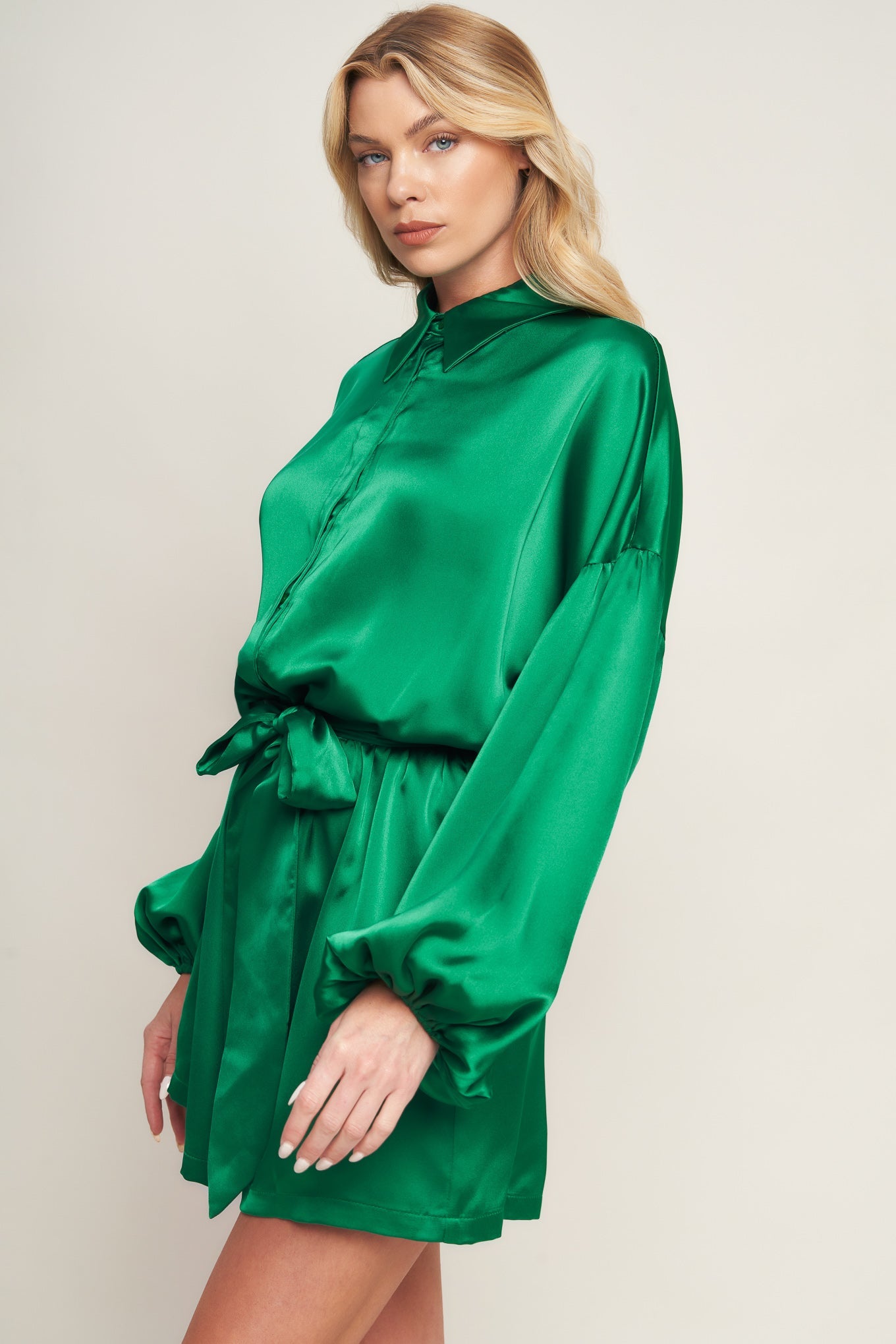 Emerald green satin romper with bishop sleeves, shirt collar, and tie waist for holiday celebrations and special events