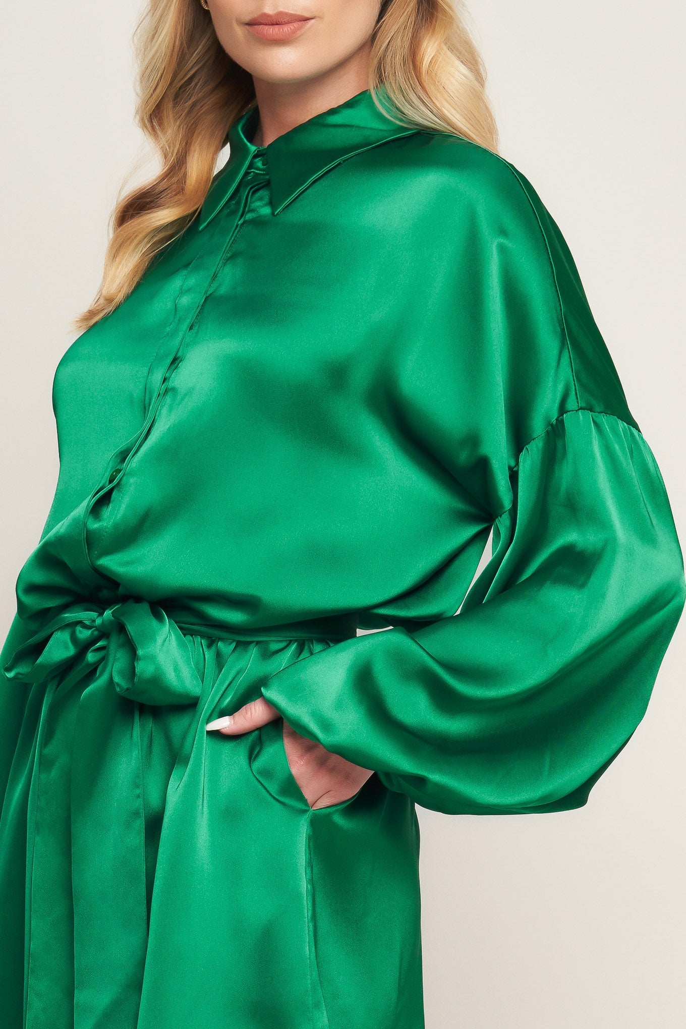 Emerald green satin romper with bishop sleeves, shirt collar, and tie waist for holiday celebrations and special events