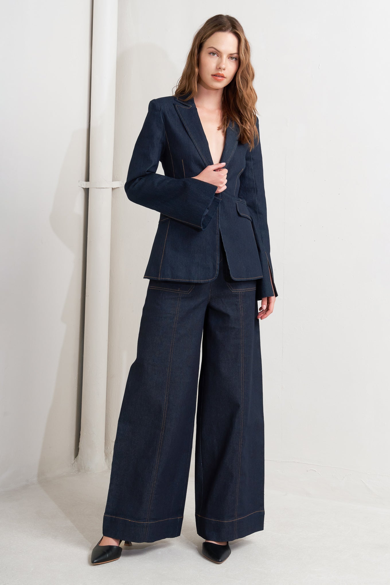 Woman wearing a navy blue suit with wide-leg pants on a white background
