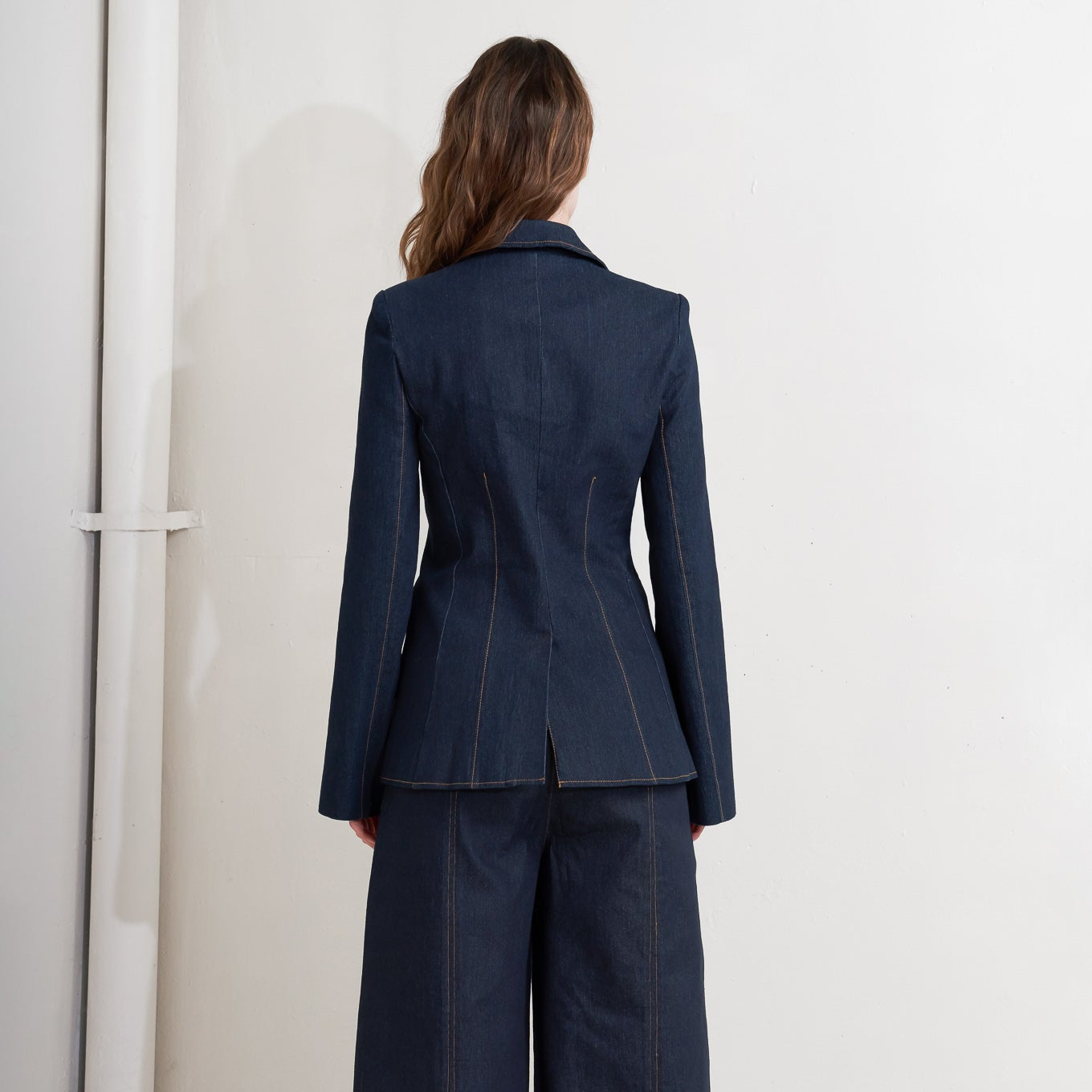 Person wearing a navy blue suit standing against a white background
