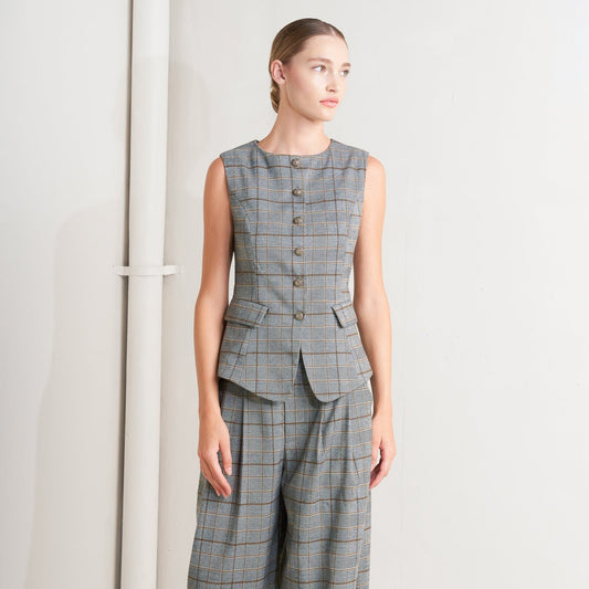 Woman wearing a gray plaid sleeveless top and wide-leg pants against a white background