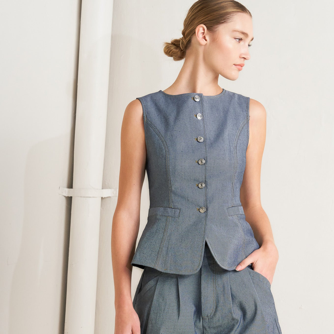 Woman wearing a denim peplum top and shorts on a plain background