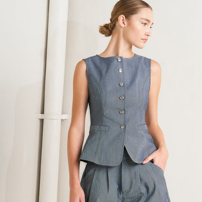 Woman wearing a denim peplum top and shorts on a plain background