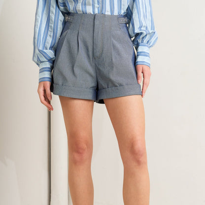 Person wearing gray shorts and a striped shirt on a plain background