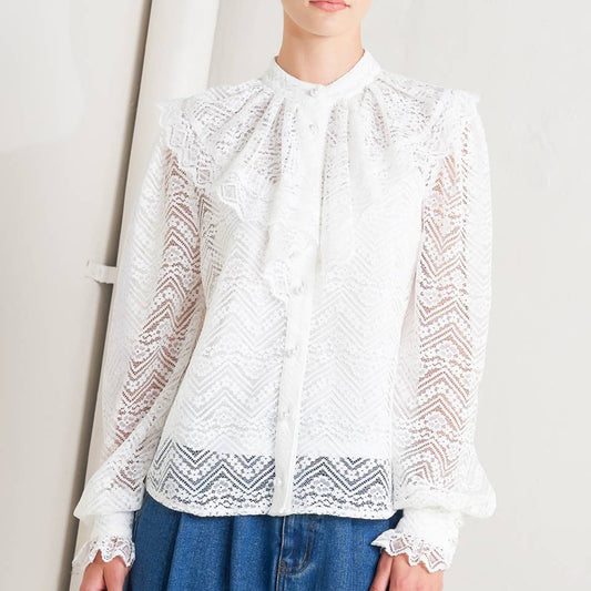 Woman wearing a white lace blouse and blue jeans against a plain background