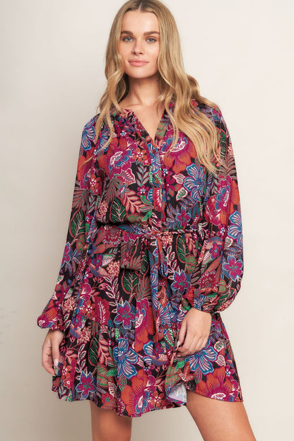 Woman wearing a colorful floral dress against a plain background