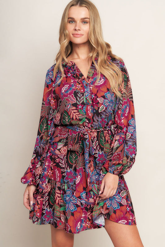 Woman wearing a colorful floral dress against a plain background