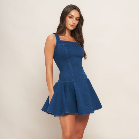 Woman wearing a blue dress and brown cowboy boots on a white background