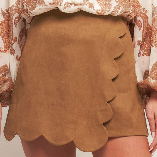 Brown suede skirt with scalloped hem on a neutral background