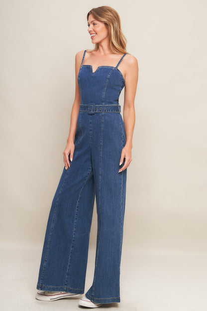 Woman wearing a blue denim jumpsuit on a beige background