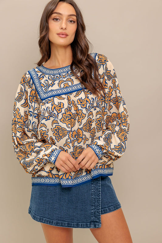 Woman wearing a patterned top and denim shorts on a beige background