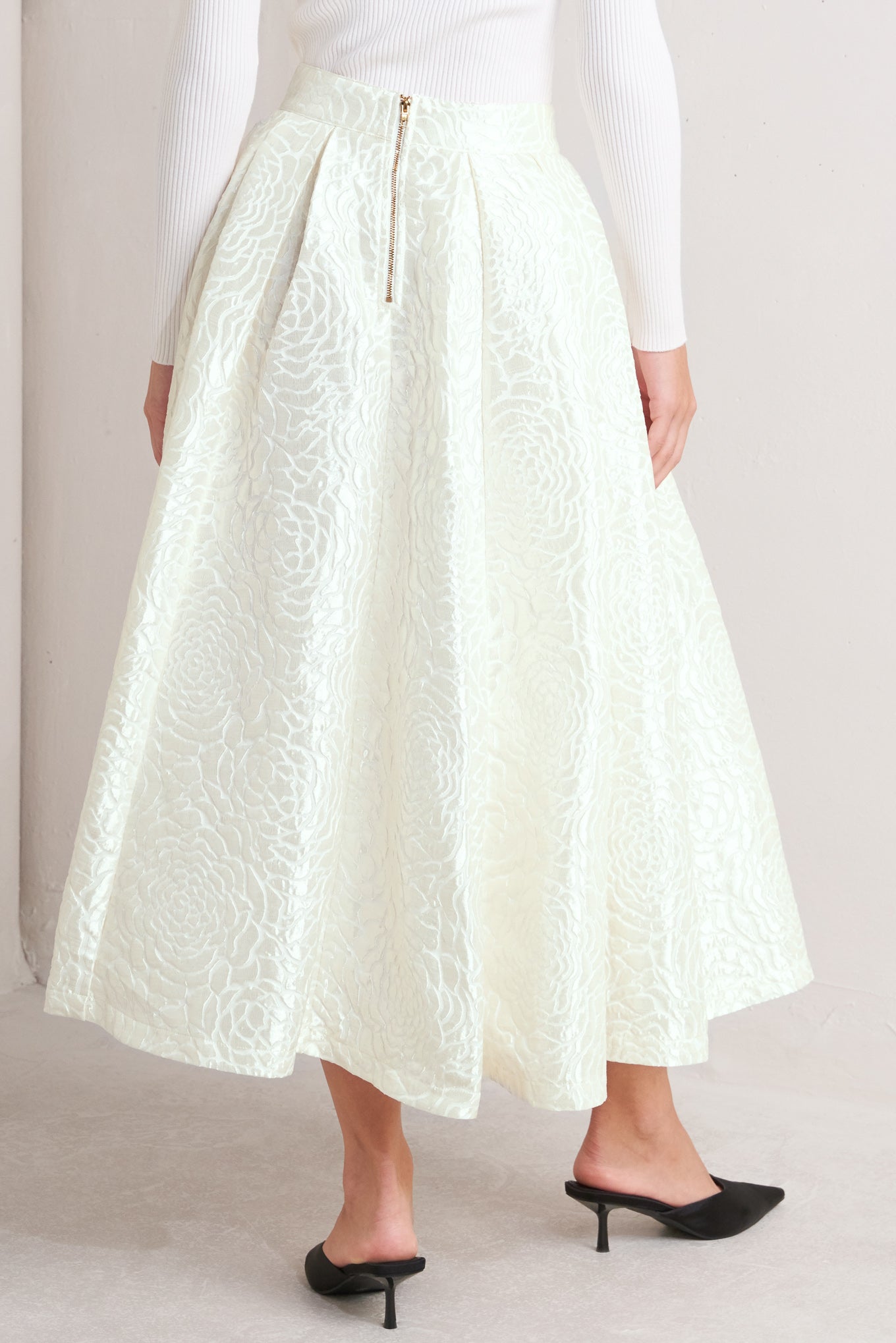 A women wearing Ivory textured jacquard pleated midi skirt with high waist and box pleats.