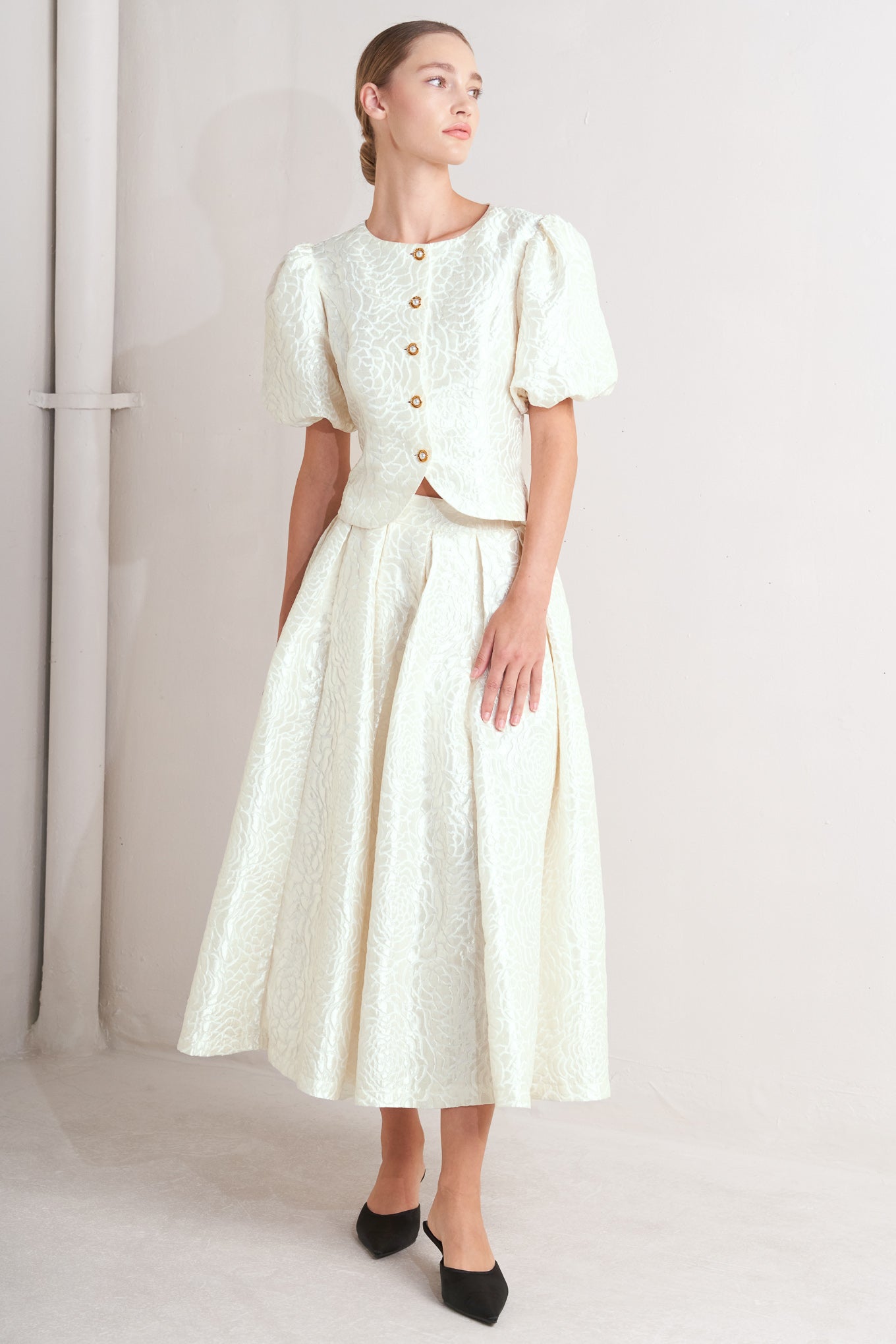 A women wearing Ivory textured jacquard pleated midi skirt with high waist and box pleats, with matching top