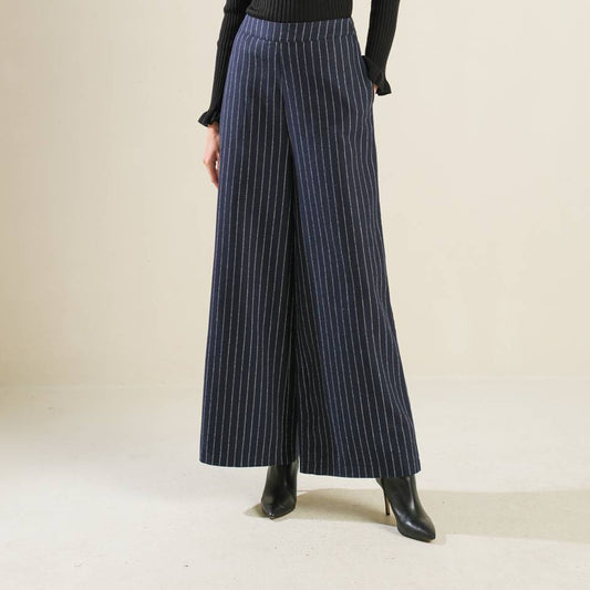 Person wearing a black turtleneck and pinstripe pants on a plain background