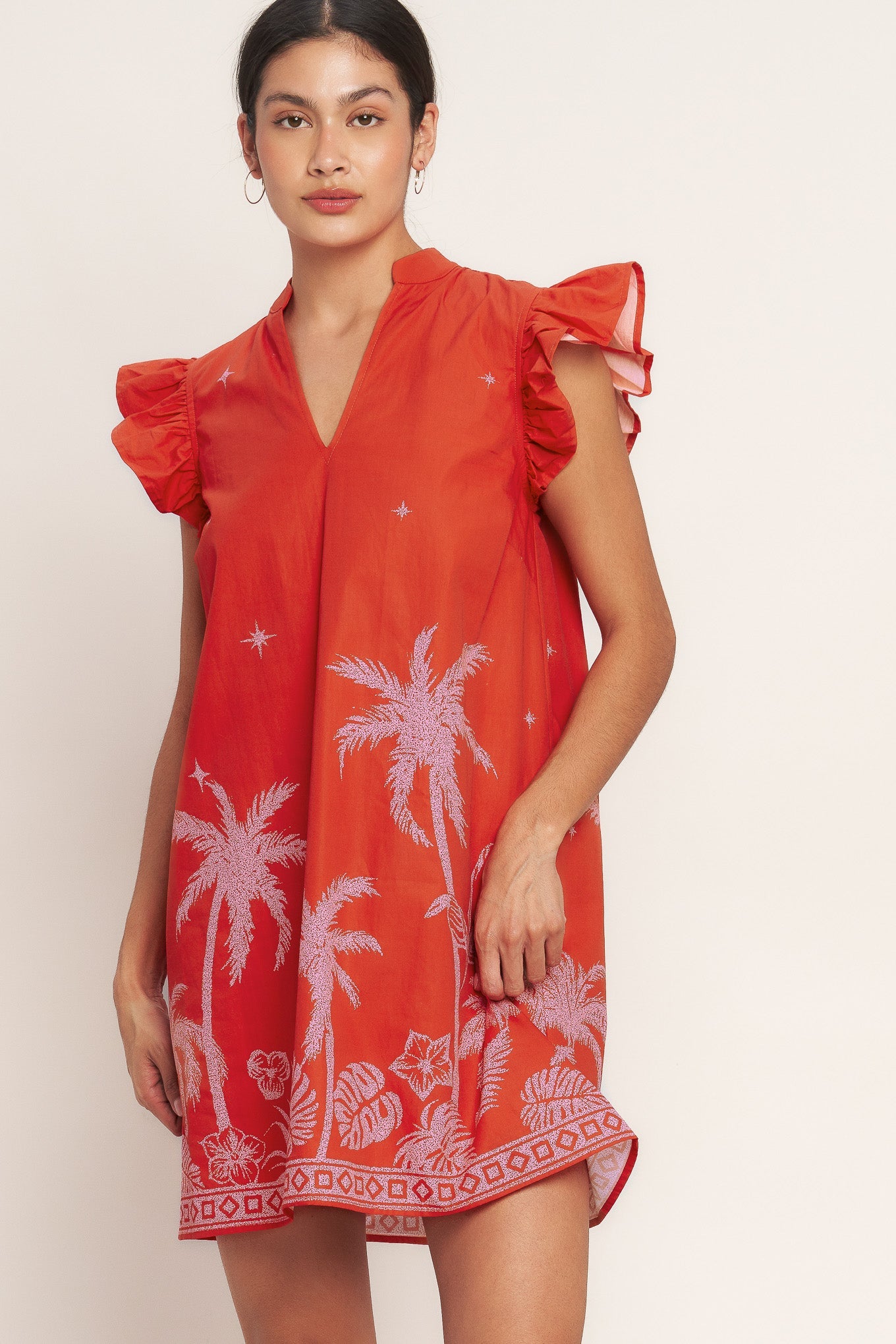 Woman wearing a Coral mini dress with pink palm tree embroidery, V-neck, and ruffle sleeves for beach vacation and tropical resort wear
This show-stopping dress brings instant vacation energy to your wardrobe, offering a bold statement piece that captures the carefree spirit of tropical destinations with vibrant color and playful embroidered details.​​​​​​​​​​​​​​​​