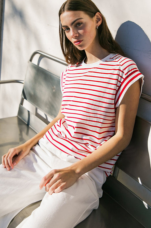 Woman wearing a red and white striped shirt sitting on a bench.